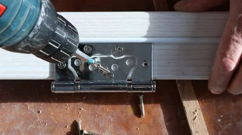 Manual work with a screwdriver in the process of fixing the hinges Stock Photos