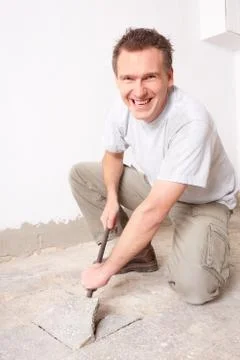 Manual worker disassembling old floor tiles Stock Photos