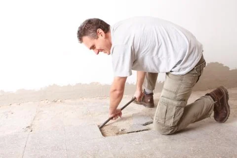 Manual worker disassembling old floor tiles Stock Photos