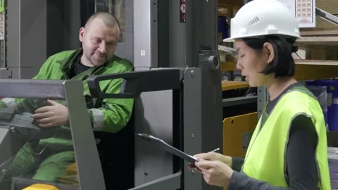 Manual worker on forklift loader and manager with clipboard at industrial Stock Footage 148149121