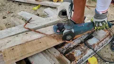 Manual worker with grinder bosch tool to cut rusty iron  rod with sparks Stock Footage 241197459