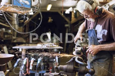 Manual worker using grinder at workshop Stock Photos
