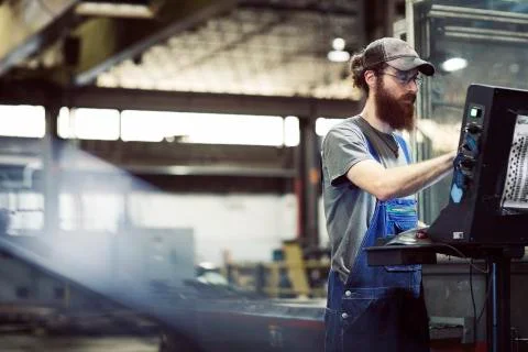 Manual worker wearing cap while using desktop computer in steel industry Stock Photos