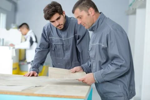 Manual workers looking at paperwork spread over desk Stock Photos