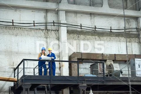 Manual workers working with blueprint at factory Stock Photos