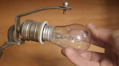Manually screwing lightbulb into table lamp socket 4K video Stock Footage 139480949