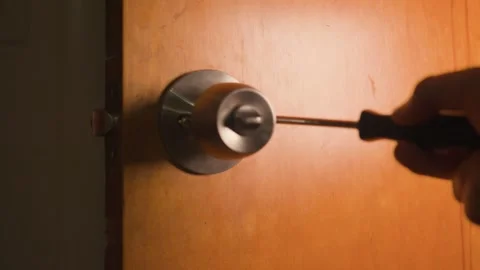 Manually securing the handle screws on the inside section of the door knob. Stockbeeldmateriaal 327336132