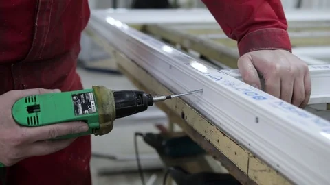 Manufacture of plastic windows and doors. Worker fastens the fittings with a scr Stock Footage 100877135