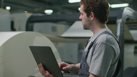 Manufacturing Engineer Checking Web-Fed Press with Laptop in Print Shop Stock Footage 335483888