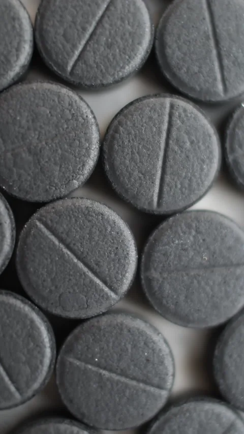 Many activated coal tablets rotating, on white background. Vertical video. Stock Footage 274206999