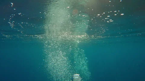 Many air bubbles rising to surface and reflecting in water, illuminated by Stock Footage 336572638
