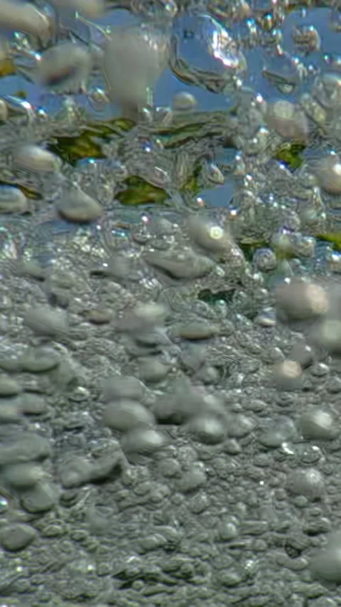 Many air bubbles rushing below surface of mountain river in front of blue sky, Stock Footage 331611163