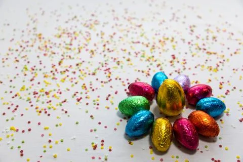 Many aligned colored chocolate easter eggs on white background and colorful c Foto stock