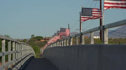 Many American flags line a bridge on a rural road Stock Footage 275825830