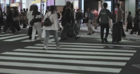 Many anonymous people cross pedestrian crossing in night city. Pedestrians Stock Footage 334907913
