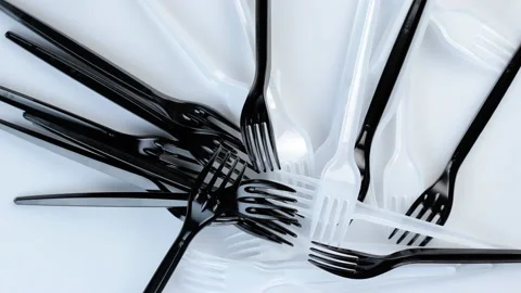 Many black plastic disposable forks spin on a white background. Видео 145651475