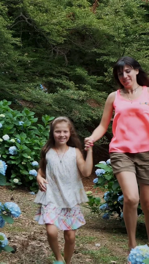 Many blooming hydrangea bushes grow in the park. The girl, kid, and woman, Stock Footage 314659090