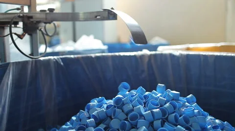Many blue plastic bottle caps fall from conveyor to the box. Video stock 56227149