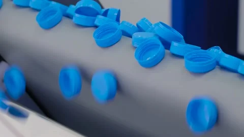 Many blue plastic bottle caps falling from conveyor belt - close up Vidéo 153796689