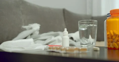 Many bottles of pills tablets and a glass of water on the table at home Stock Footage 130043965