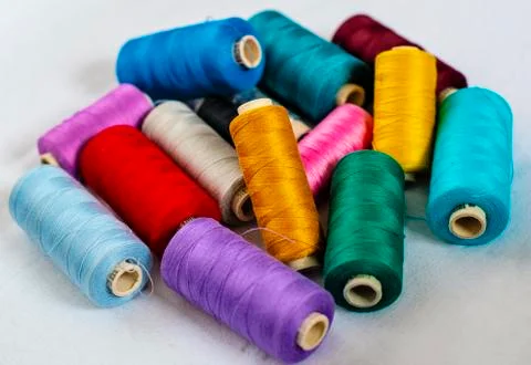 Many bright color thread spools on white fabric - image Foto stock