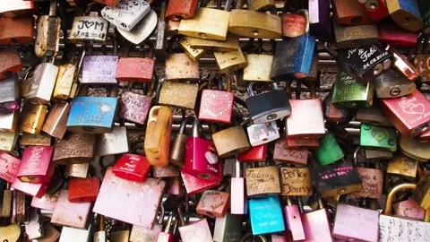 Many bright, colored iron locks are attached to the fence on the bridge. Stock Footage 136035988