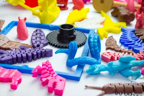 Many bright multi-colored objects printed on 3d printer lie on flat surface Foto stock