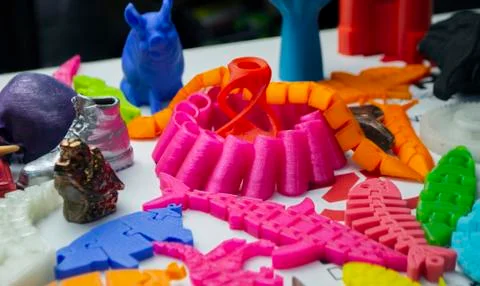 Many bright multi-colored objects printed on 3d printer lie on flat surface Stock Photos