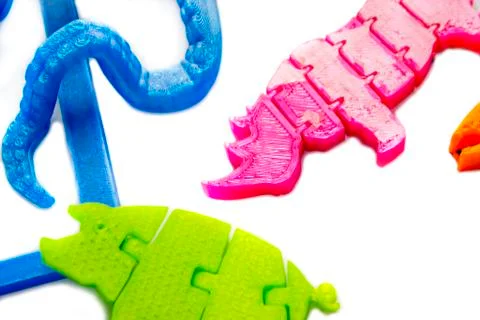Many bright multi-colored objects printed on 3d printer lie on flat surface Foto stock