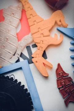 Many bright multi-colored objects printed on 3d printer lie on flat surface Foto stock