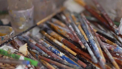 Many brushes stained with paint are on the table in the artist's Studio. Video stock 124899265