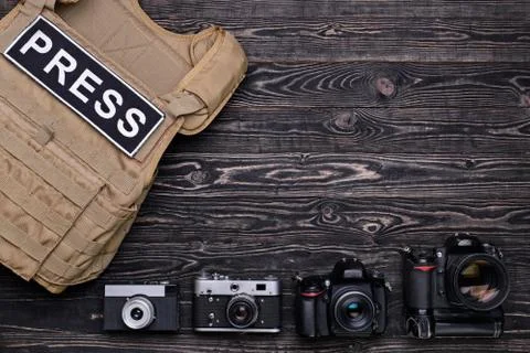 Many cameras and body armor on wooden table Stock Photos