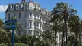 Many cars passing by building in Nice on sunny day, palm trees swaying in wind 4k or 4k+ Resolution
