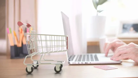 Many cartons with FEDEX logo fall in shopping trolley near customer with laptop Stock Footage 127653925