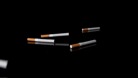 Many cigarettes throwing down on black mirroring surface in slow motion. Stock Footage 146948750