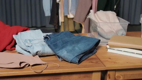 Many clothes lay on table in second hand shop Video stock 159729558