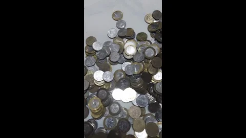 Many coins are scattered on a table in an indoor space during daylight hours Stock Footage 326374909