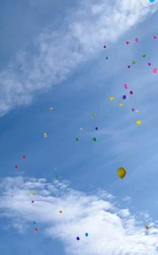 Many colored balloons fly in the blue sky with clouds Stock Photos