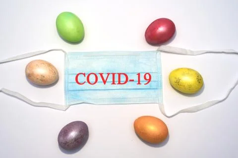 Many colored easter eggs laying around medical mask. Stock Photos