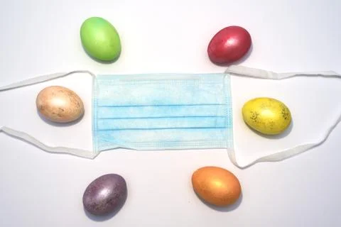 Many colored easter eggs laying around medical mask. Stock Photos