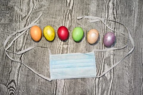 Many colored easter eggs laying near medical mask. Stock Photos