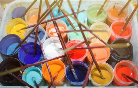Many colored open cans with paint and a brush, top view. Foto stock