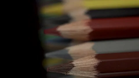 Many colored pencils lie in a row on a black background. The camera moves Stock Footage 131214751