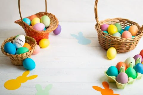 Many colorful Easter eggs in wicker basket with paper bunnies garland 스톡 사진