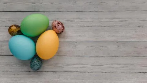 Many colorful painted Easter eggs on light wooden background, top view. Space Stock Photos