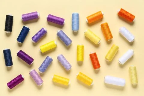 Many colorful thread spools on beige background 写真素材
