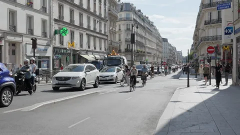 Many commuters ride bicycles along a busy city street with active road traffic Stock Footage 336721846