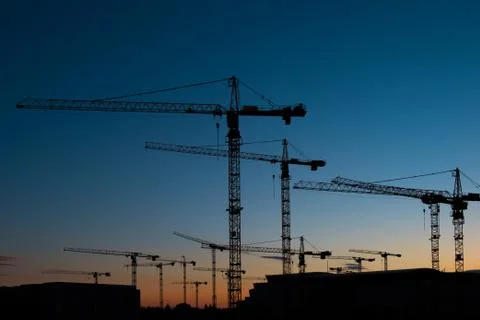 Many construction cranes on sunset sky , crane silhouette skyline 写真素材