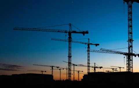 Many construction cranes on sunset sky , crane silhouette skyline Stock Photos