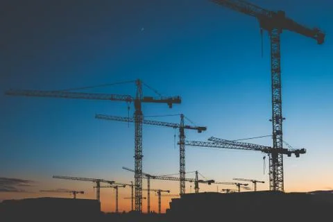Many construction cranes on sunset sky , crane silhouette skyline 写真素材